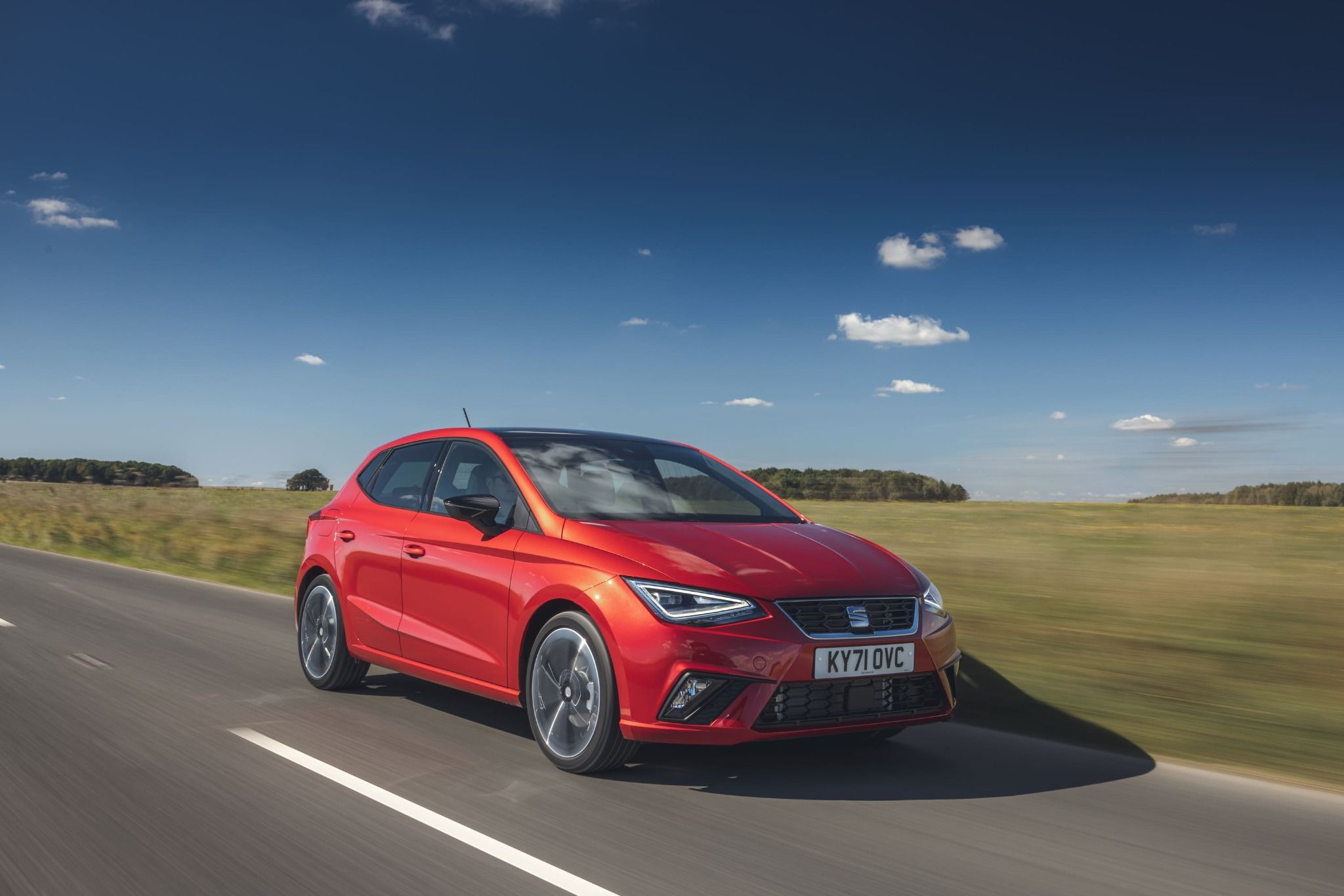 Red SEAT Ibiza driving down a road