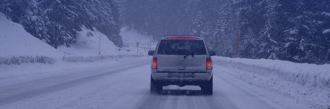 rear view of a car driving down a snowy road