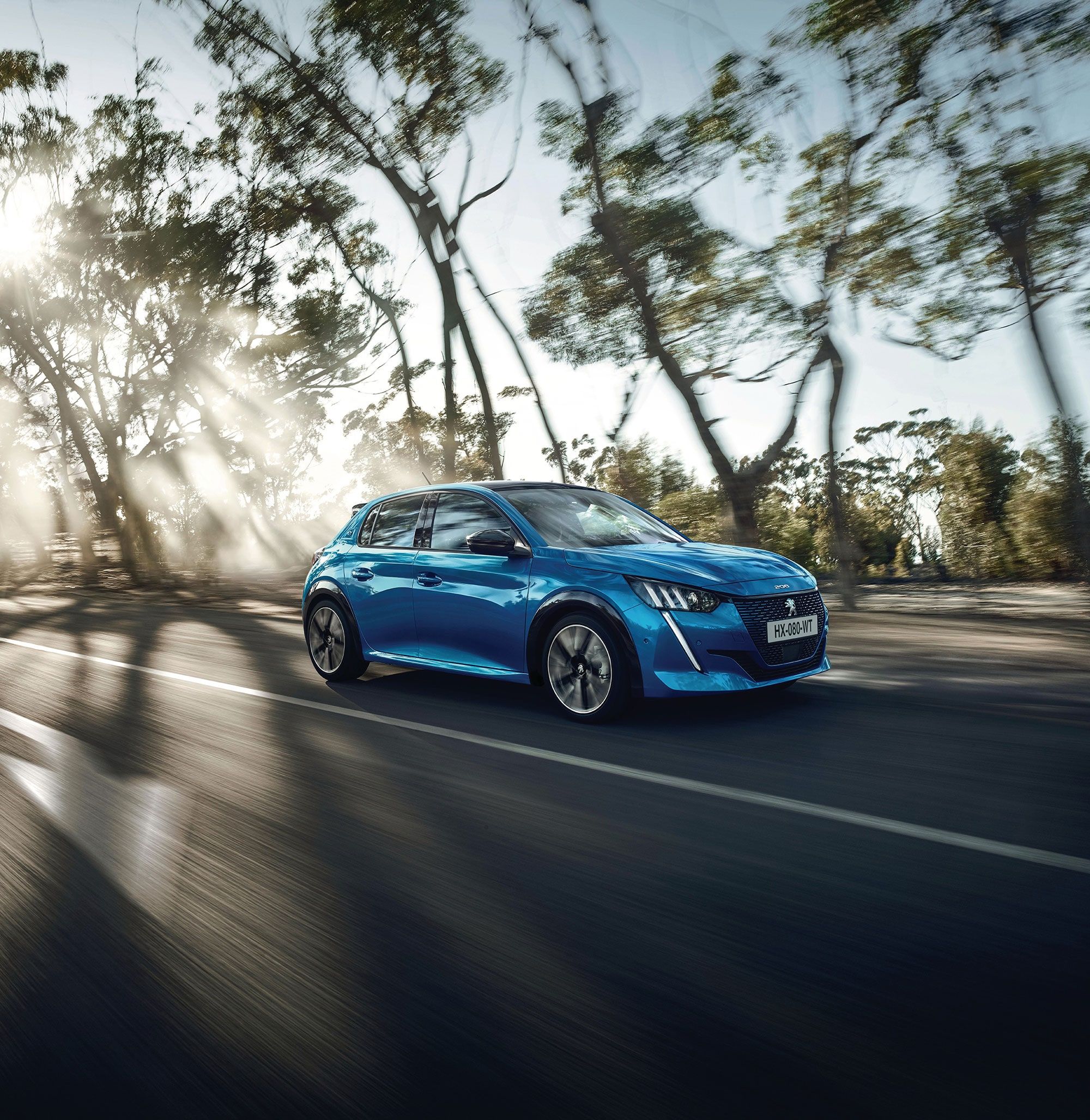 Side view of PEUGEOT 208 driving down a road