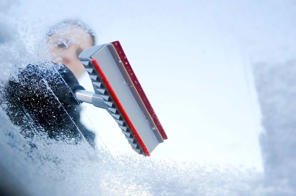 woman using an ice scraper on the windscreen