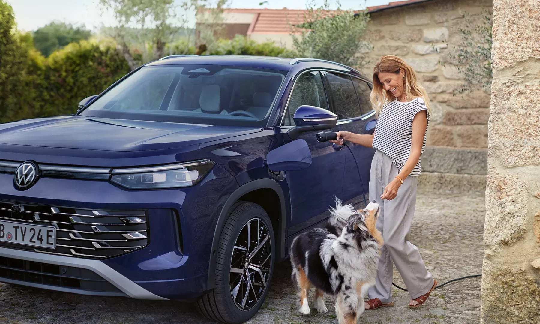 woman with dog going to charge Volkswagen tayron